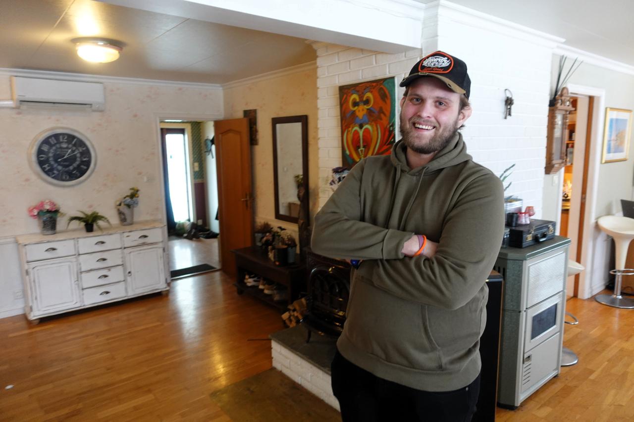 Julian Berge stående ved peisen hjemme, med armene i kors